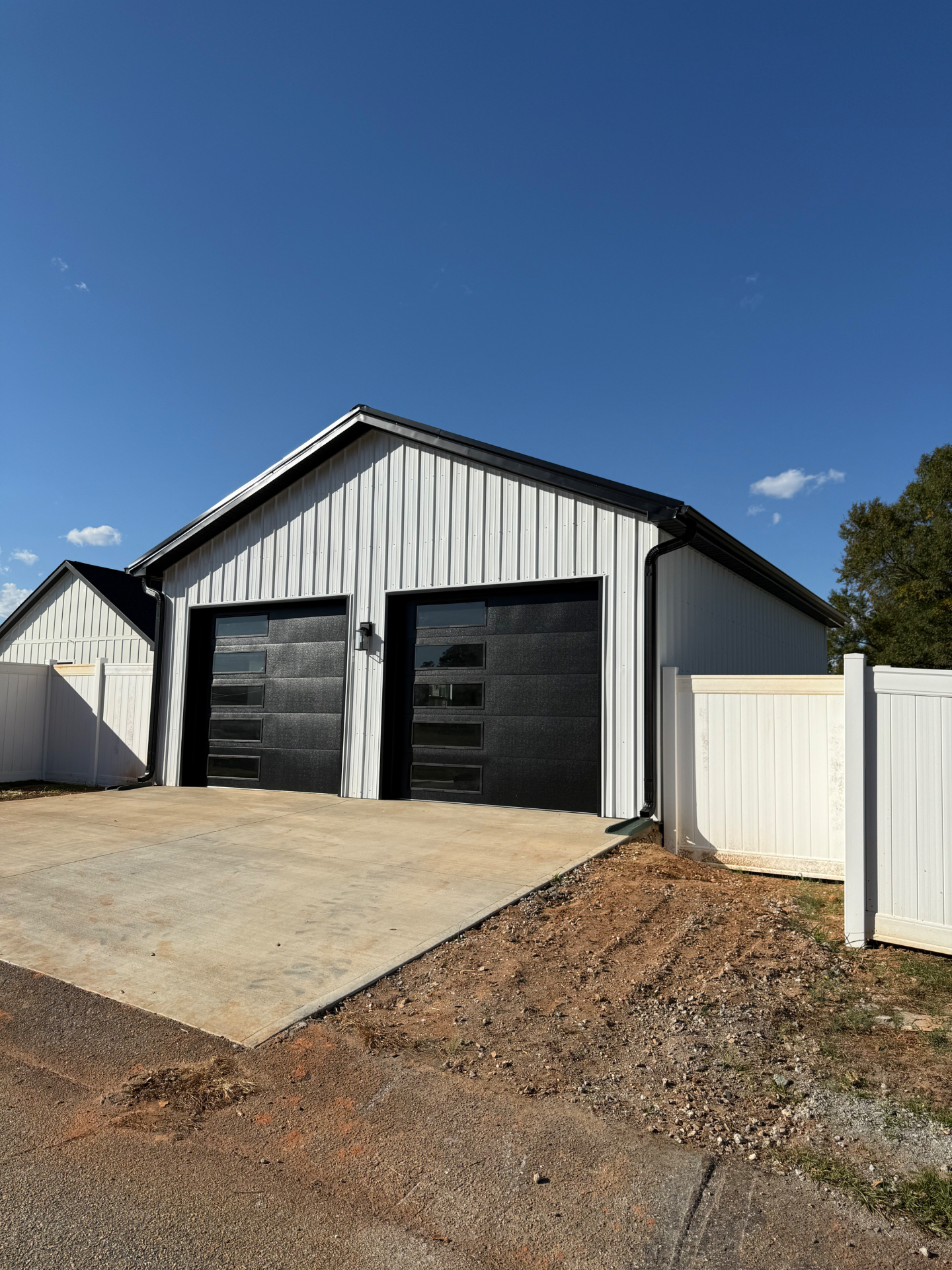 Clean white detached garage with modern black garage doors